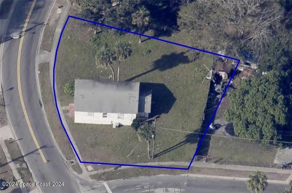 An aerial view shows a single-story house situated on a corner lot with grass — 929 S DELEON AVENUE, TITUSVILLE, FL