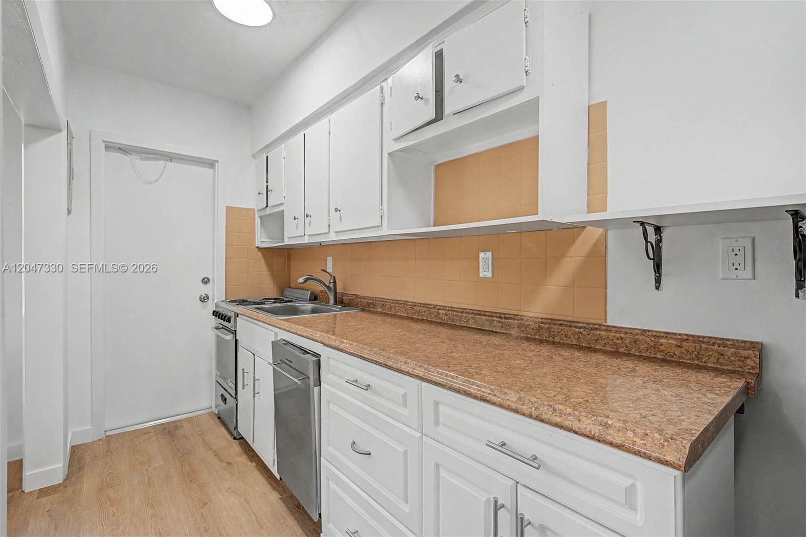 A kitchen features white cabinets, a brown laminate countertop, and tan square wall tiles — 60 NW 79th St # 27, Miami FL 33150, MIAMI, FL