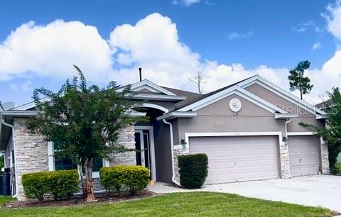 A single-story house with a stone facade, a three-car garage, and a manicured lawn — 1435 DAYSTAR LANE, DELTONA, FL
