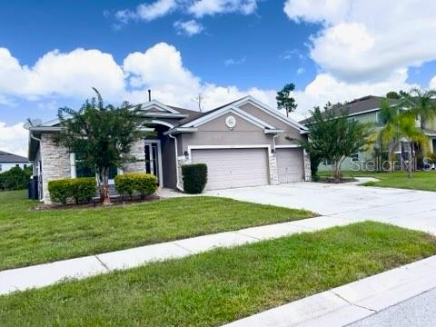 A single-story house with a stone facade, a three-car garage, and a manicured front lawn — 1435 DAYSTAR LANE, DELTONA, FL