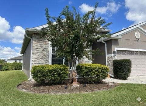 A single-story house exterior features stone siding, a front yard tree, and a garage — 1435 DAYSTAR LANE, DELTONA, FL