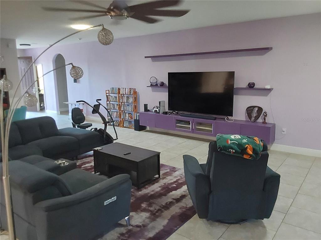A living room features a purple media console, floating shelves, a television, and dark furniture — 1435 DAYSTAR LANE, DELTONA, FL