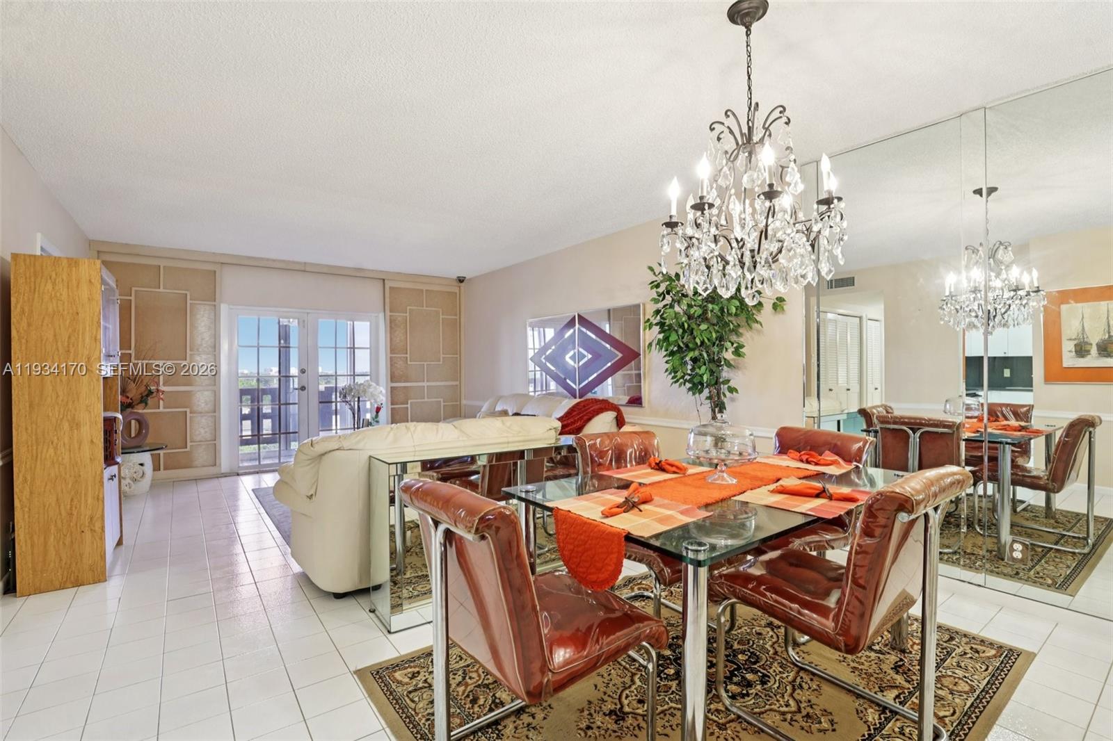 A dining area with a glass table, chandelier, and mirrored wall opens to a living room — 4350 Hillcrest Dr # 702, Hollywood FL 33021, HOLLYWOOD, FL