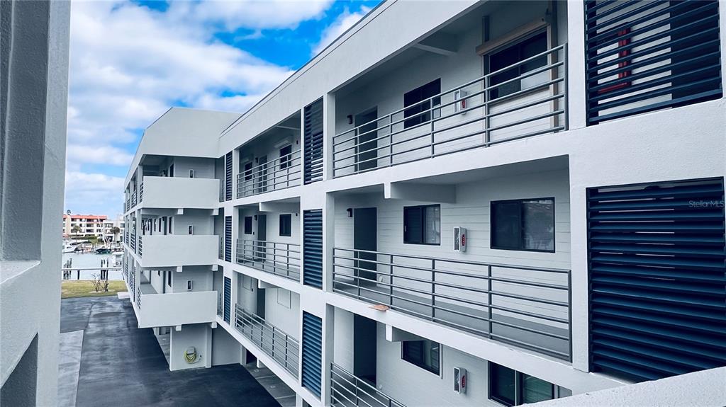An exterior view of a multi-story apartment building with open-air walkways and metal railings — 363 PINELLAS BAYWAY S UNIT 36, TIERRA VERDE, FL