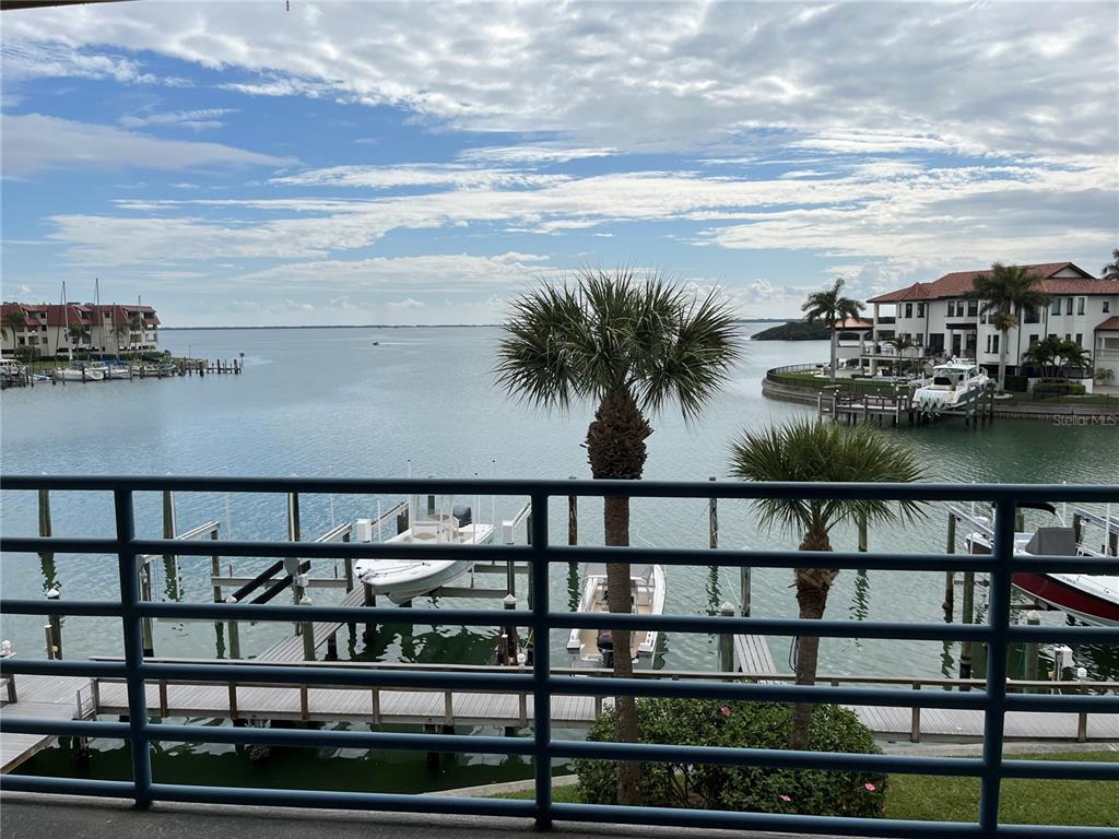 A balcony view overlooks a marina with boats, palm trees, and waterfront homes — 363 PINELLAS BAYWAY S UNIT 36, TIERRA VERDE, FL