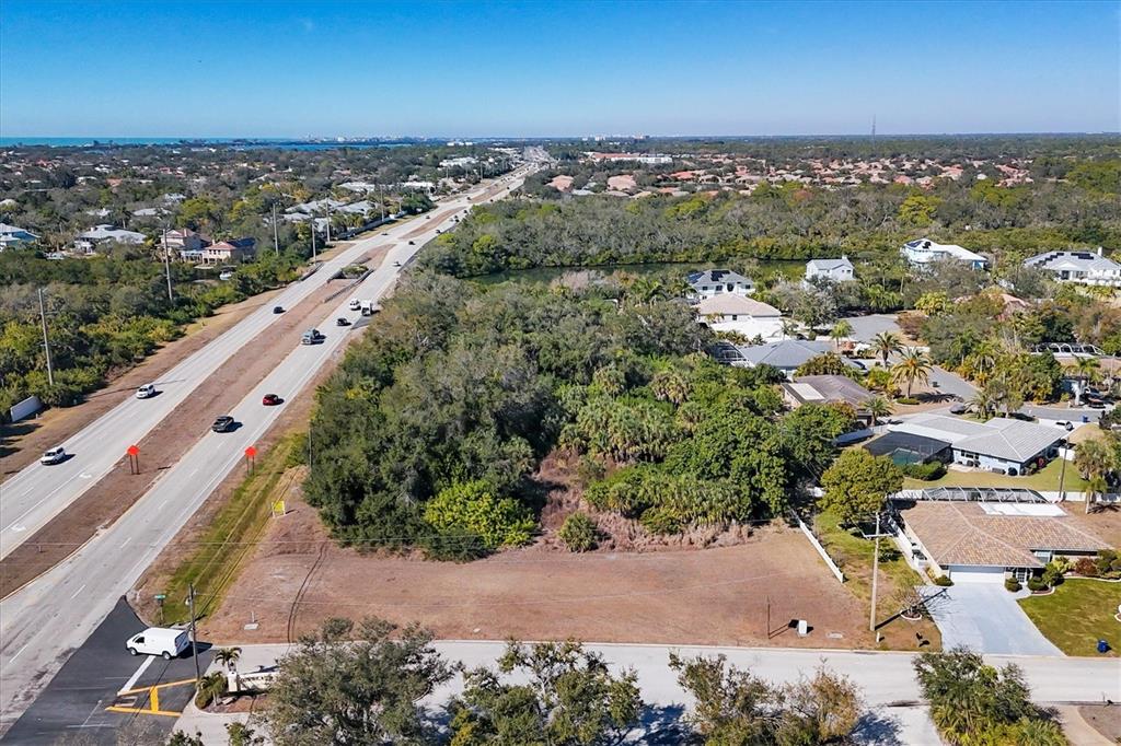 An aerial view shows a vacant rectangular lot adjacent to a highway and residential homes — 2099 S TAMIAMI TRAIL, OSPREY, FL