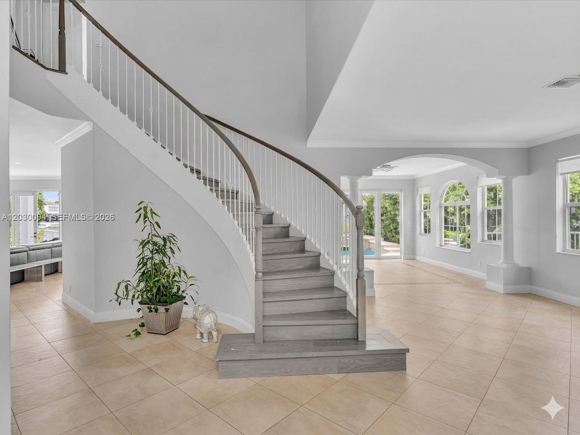 A curved wooden staircase with white railings stands in a bright, tiled foyer — 4971 SW 158th Ave, Miramar FL 33027, MIRAMAR, FL