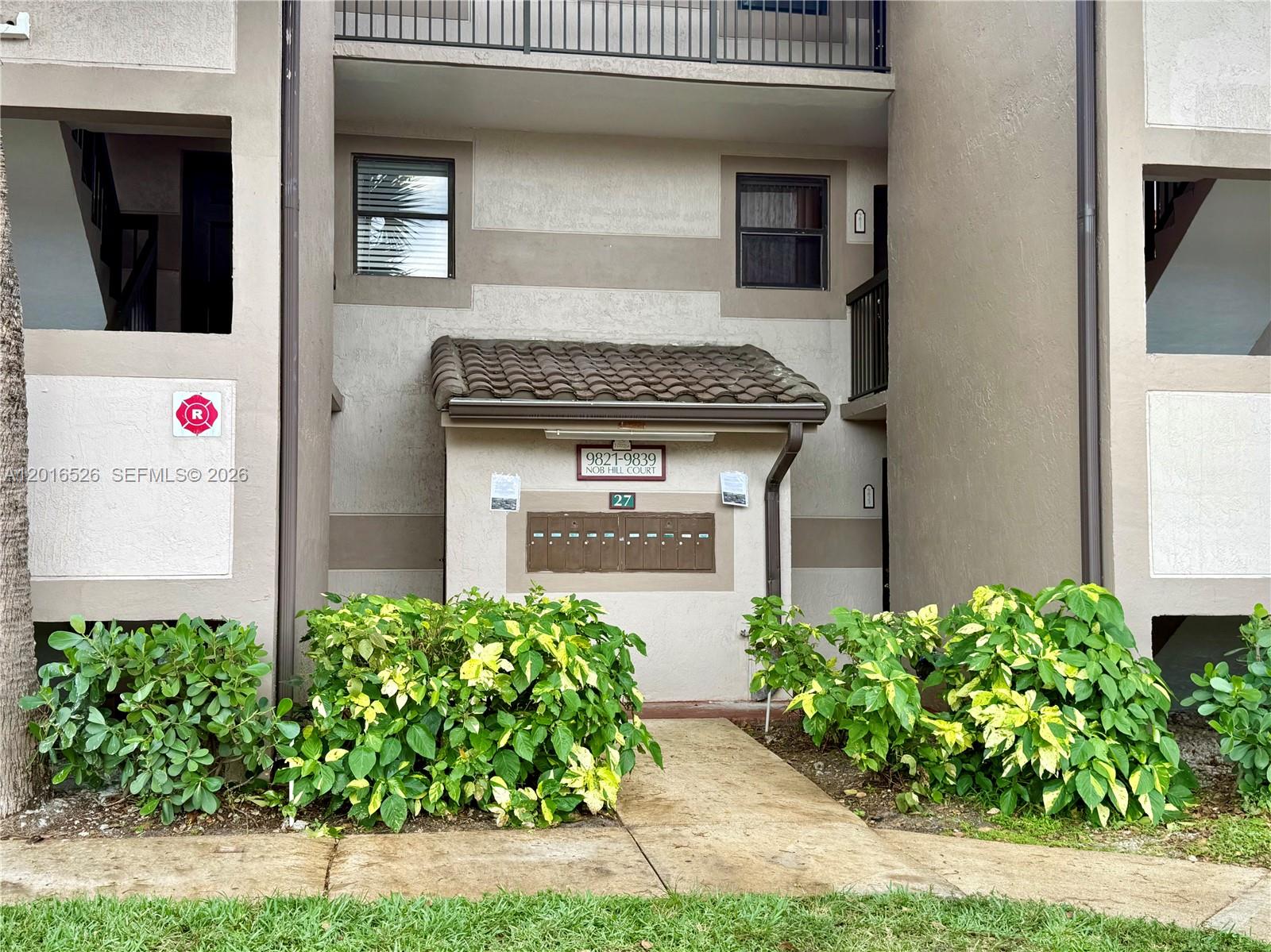 An exterior view of a multi-unit residential building featuring a central cluster of mailboxes — 9827 Nob Hill Ct # 0, Sunrise FL 33351, SUNRISE, FL
