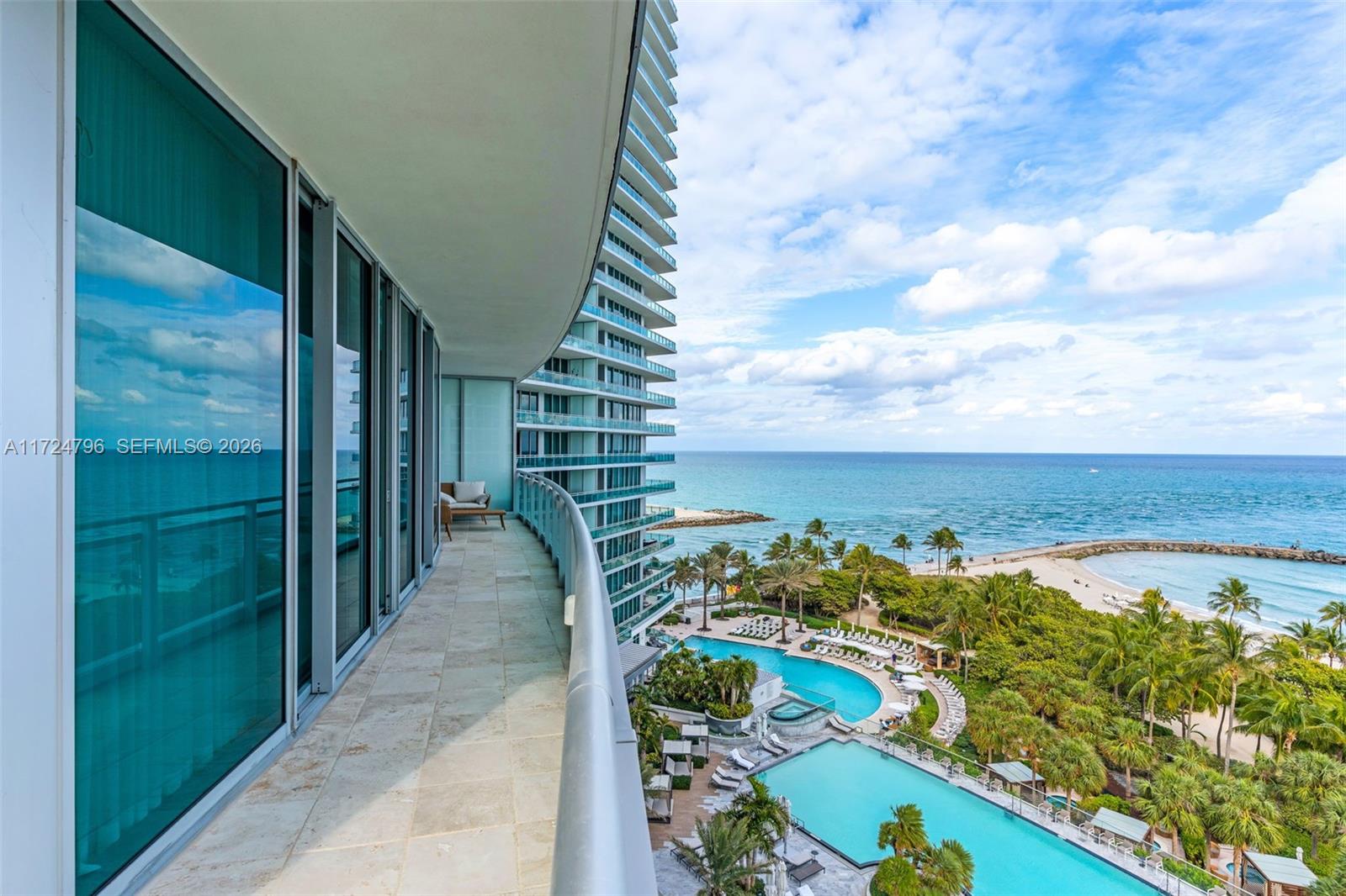 A curved balcony overlooks a swimming pool complex and the ocean — 10295 Collins Ave # 701, Bal Harbour FL 33154, BAL HARBOUR, FL