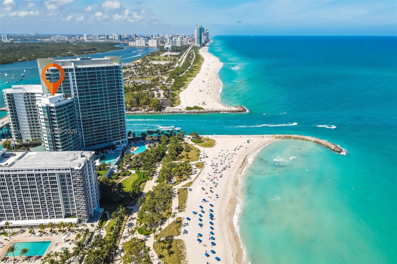 An aerial view shows high-rise residential buildings situated along a sandy beach and ocean inlet — 10295 Collins Ave # 701, Bal Harbour FL 33154, BAL HARBOUR, FL
