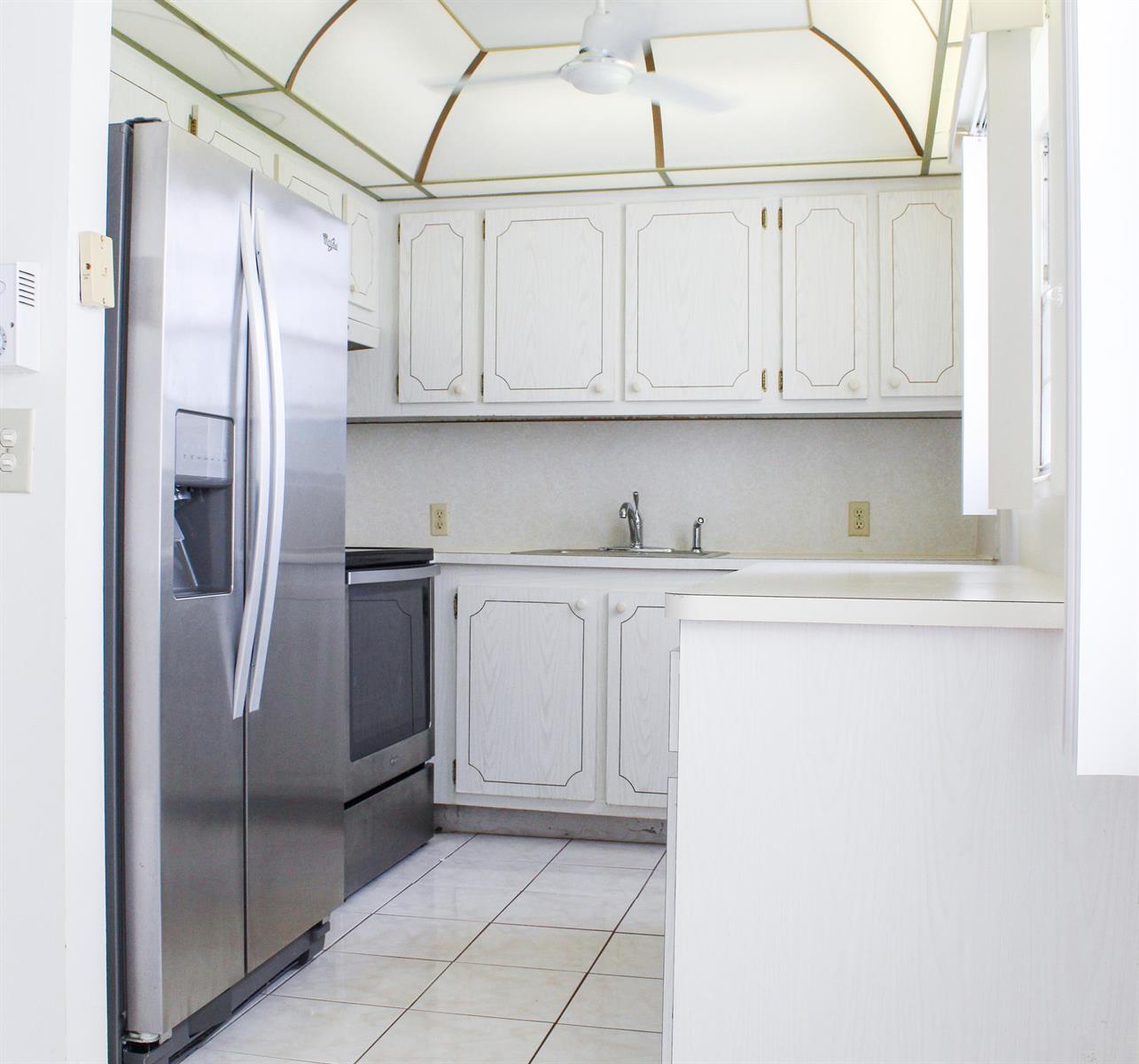 A kitchen with white cabinets, stainless steel appliances, tile flooring, and a vaulted ceiling — 66 Brighton, Boca Raton FL 33434, BOCA RATON, FL