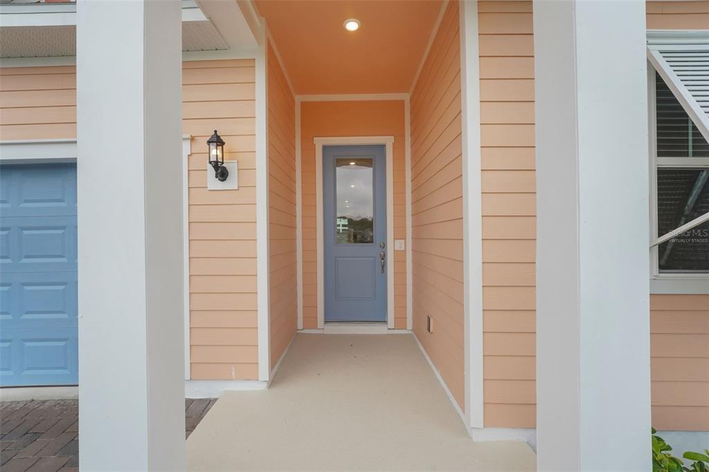 A covered entryway features peach-colored siding, a blue front door, and a blue garage door — 987 FIESTA KEY CIRCLE, LADY LAKE, FL