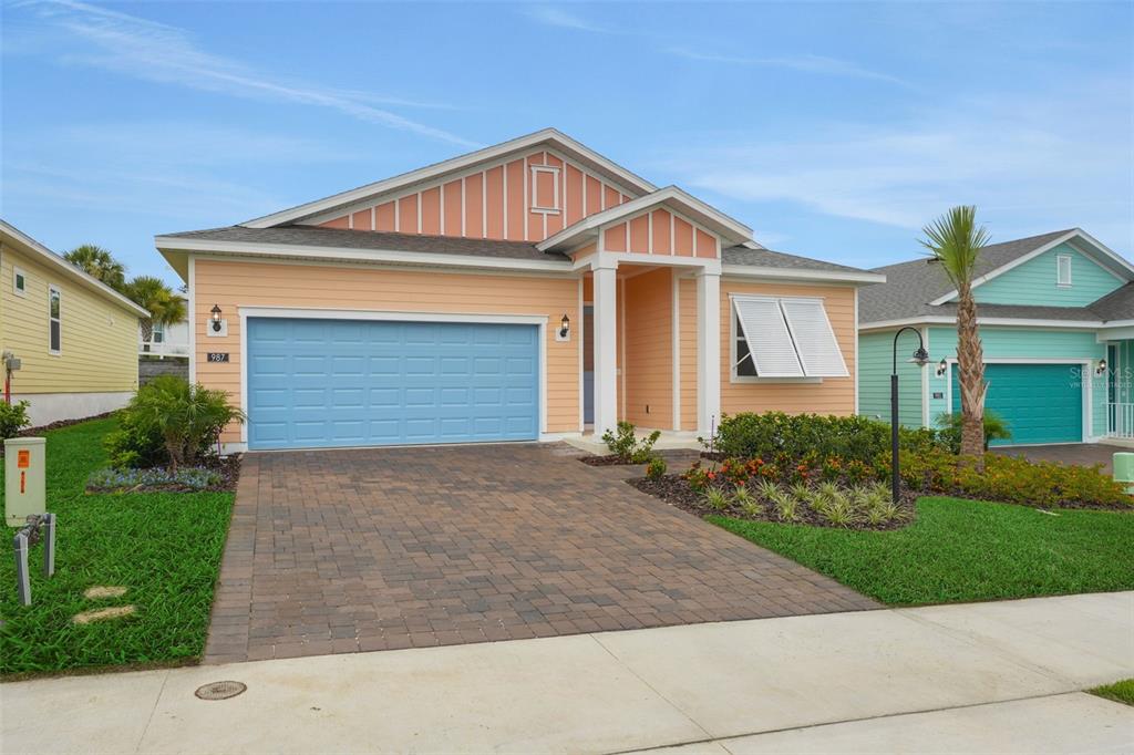 A peach-colored single-story house features a blue garage door and a brick paver driveway — 987 FIESTA KEY CIRCLE, LADY LAKE, FL