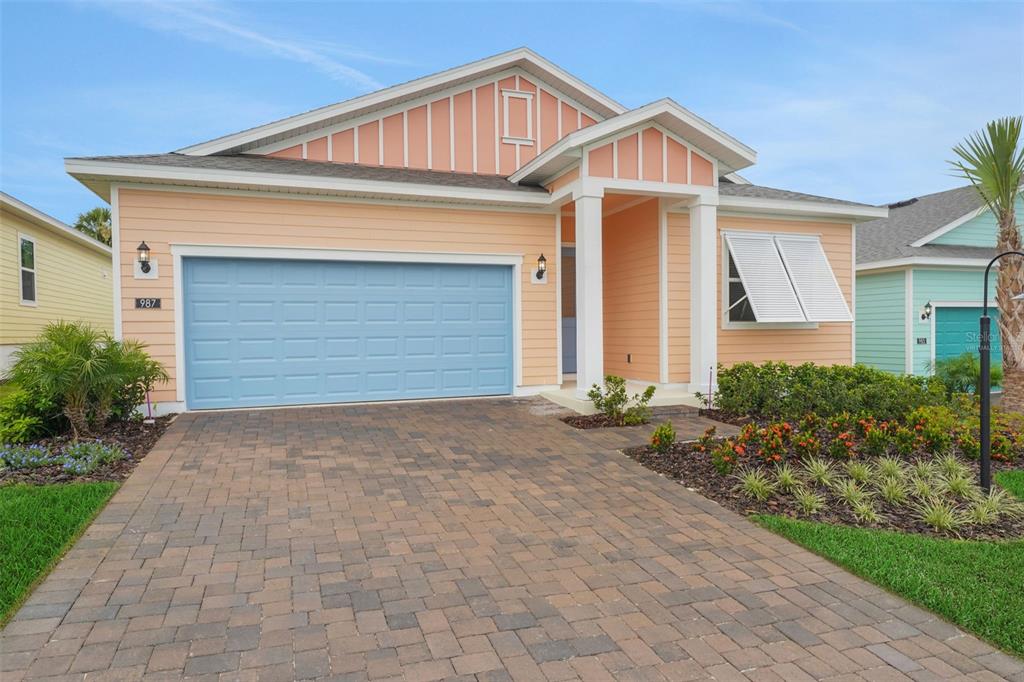 A single-story house with peach siding, a blue garage door, and a paver driveway — 987 FIESTA KEY CIRCLE, LADY LAKE, FL