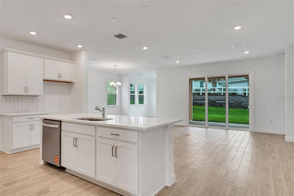A modern kitchen with white cabinets and a center island opens to a living area — 987 FIESTA KEY CIRCLE, LADY LAKE, FL