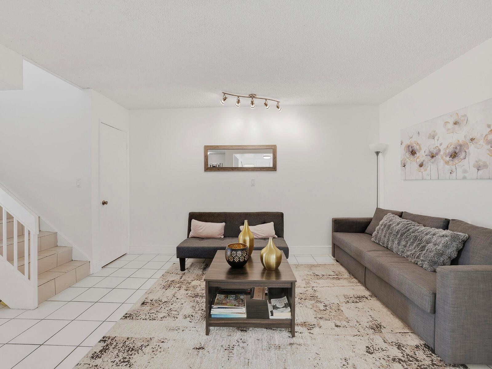 A living room with tile floors, a gray sofa, a coffee table, and a staircase — 9702 NW 5th Lane # 9702, Miami FL 33172, MIAMI, FL