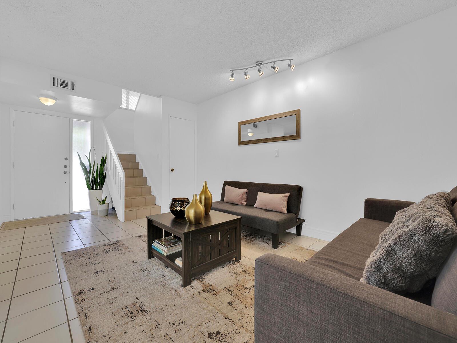 A living room features a dark sofa, a coffee table, and stairs leading to an upper level — 9702 NW 5th Lane # 9702, Miami FL 33172, MIAMI, FL