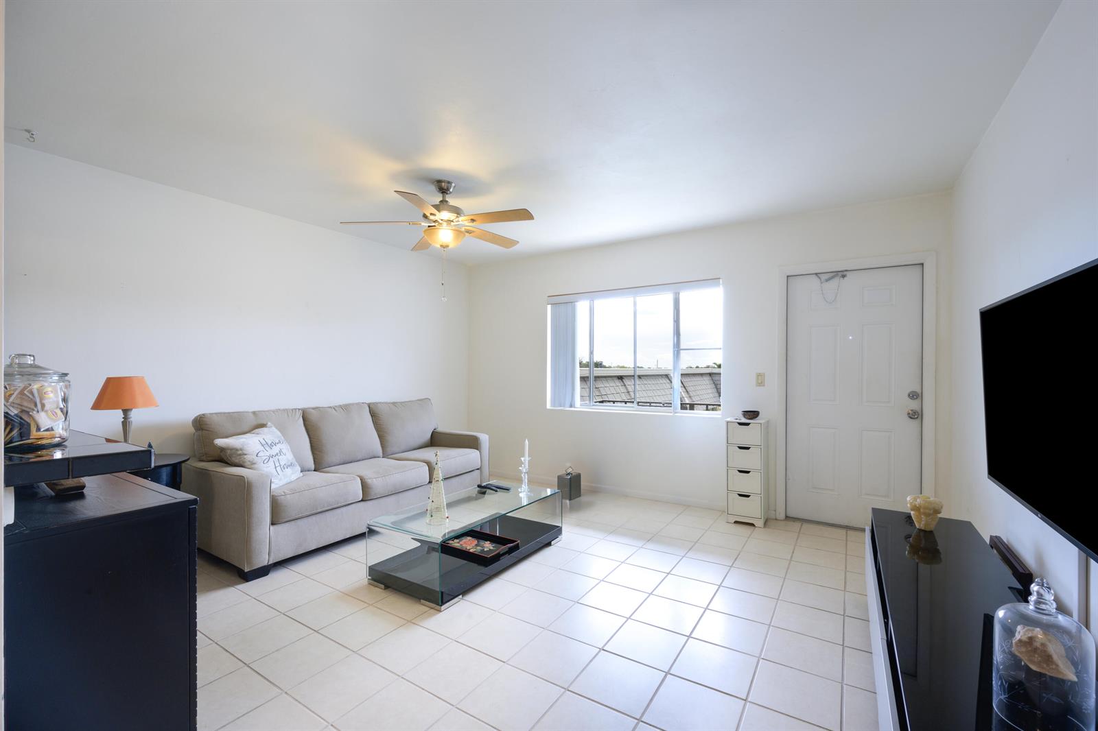 A living room features a beige sofa, glass coffee table, tile flooring, and a ceiling fan — 3402 Cynthia Lane # 208, FL 33461, FL