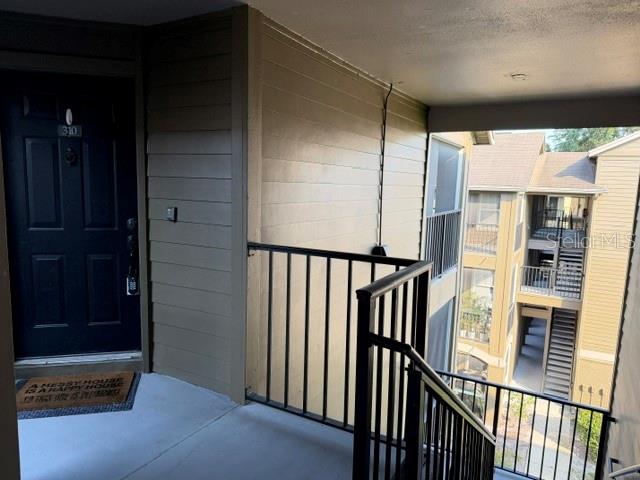 An exterior view of an apartment balcony with a dark door and metal railings — 420 SUMMIT RIDGE PLACE UNIT 310, LONGWOOD, FL