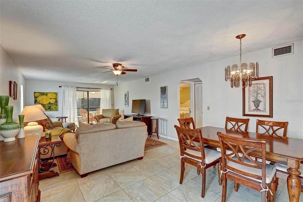 A living and dining area with tile floors, a ceiling fan, and a chandelier — 5400 34TH STREET W UNIT I9, BRADENTON, FL