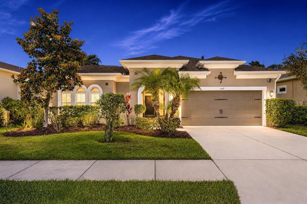 A single-story house with a two-car garage, a landscaped front yard, and a paved driveway — 6411 BLUE SAIL LANE, APOLLO BEACH, FL