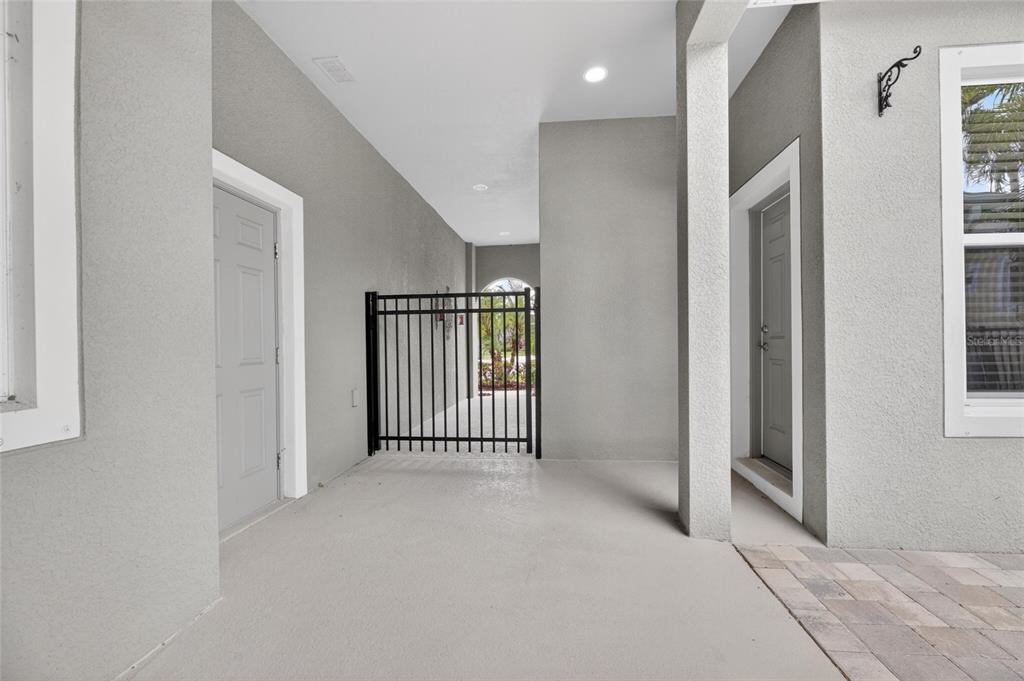 A covered patio features gray walls, a black metal gate, and two exterior doors — 6411 BLUE SAIL LANE, APOLLO BEACH, FL