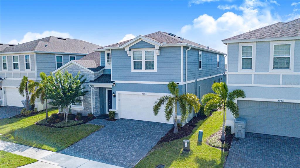 An exterior view of a two-story blue house with a paved driveway and palm trees — 2090 LELANI CIRCLE, DAVENPORT, FL