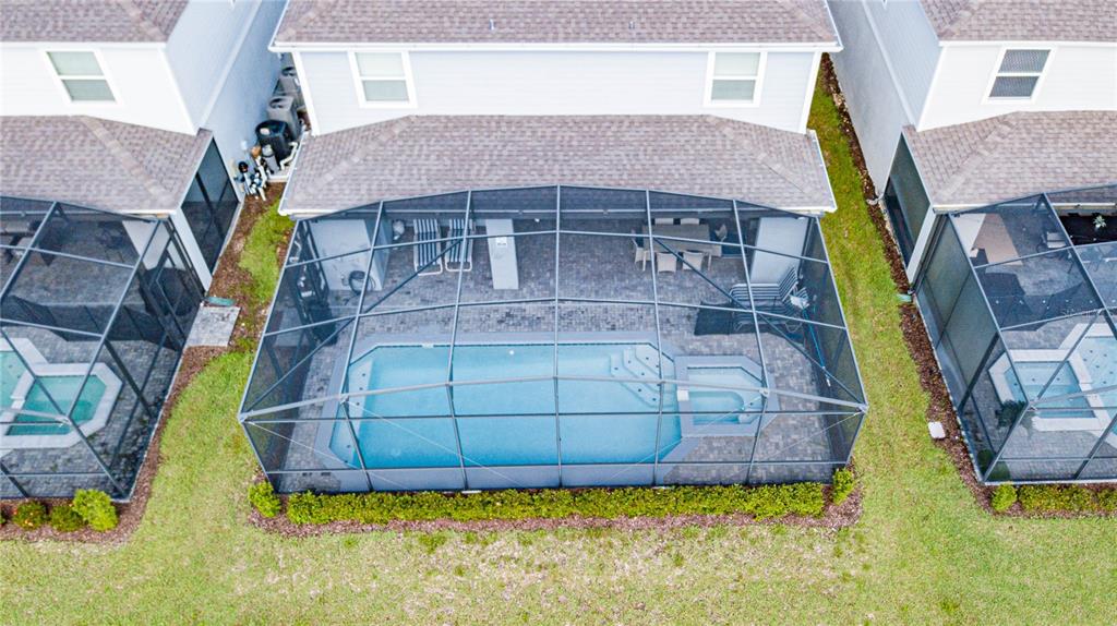 An aerial view shows a house with a screened-in pool and patio in the backyard — 2090 LELANI CIRCLE, DAVENPORT, FL