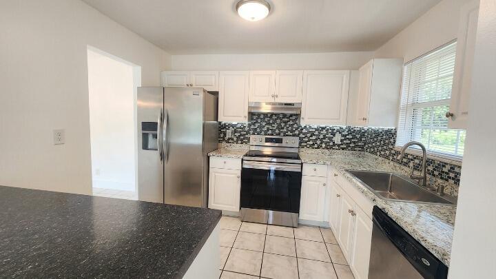 A kitchen with white cabinets, stainless steel appliances, granite countertops, and a mosaic tile backsplash — 517 Dotterel Road # 31c, Delray Beach FL 33444, DELRAY BEACH, FL