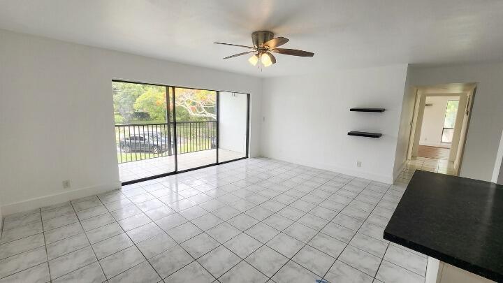 An empty living room with white tile floors, a ceiling fan, and a sliding glass door — 517 Dotterel Road # 31c, Delray Beach FL 33444, DELRAY BEACH, FL