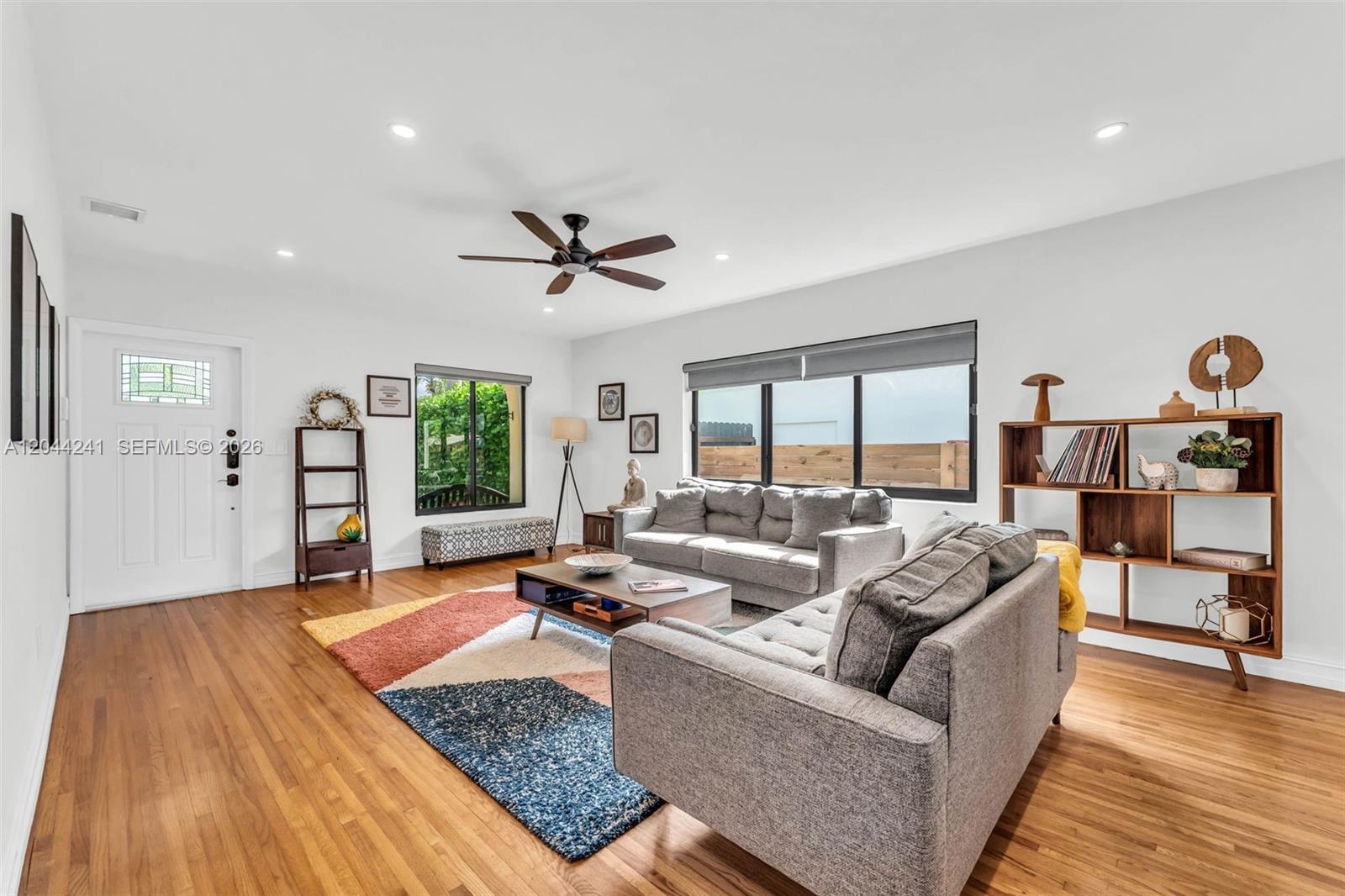 A living room features hardwood floors, a gray sofa, and a colorful geometric area rug — 2220 SW 25th St, Miami FL 33133, MIAMI, FL