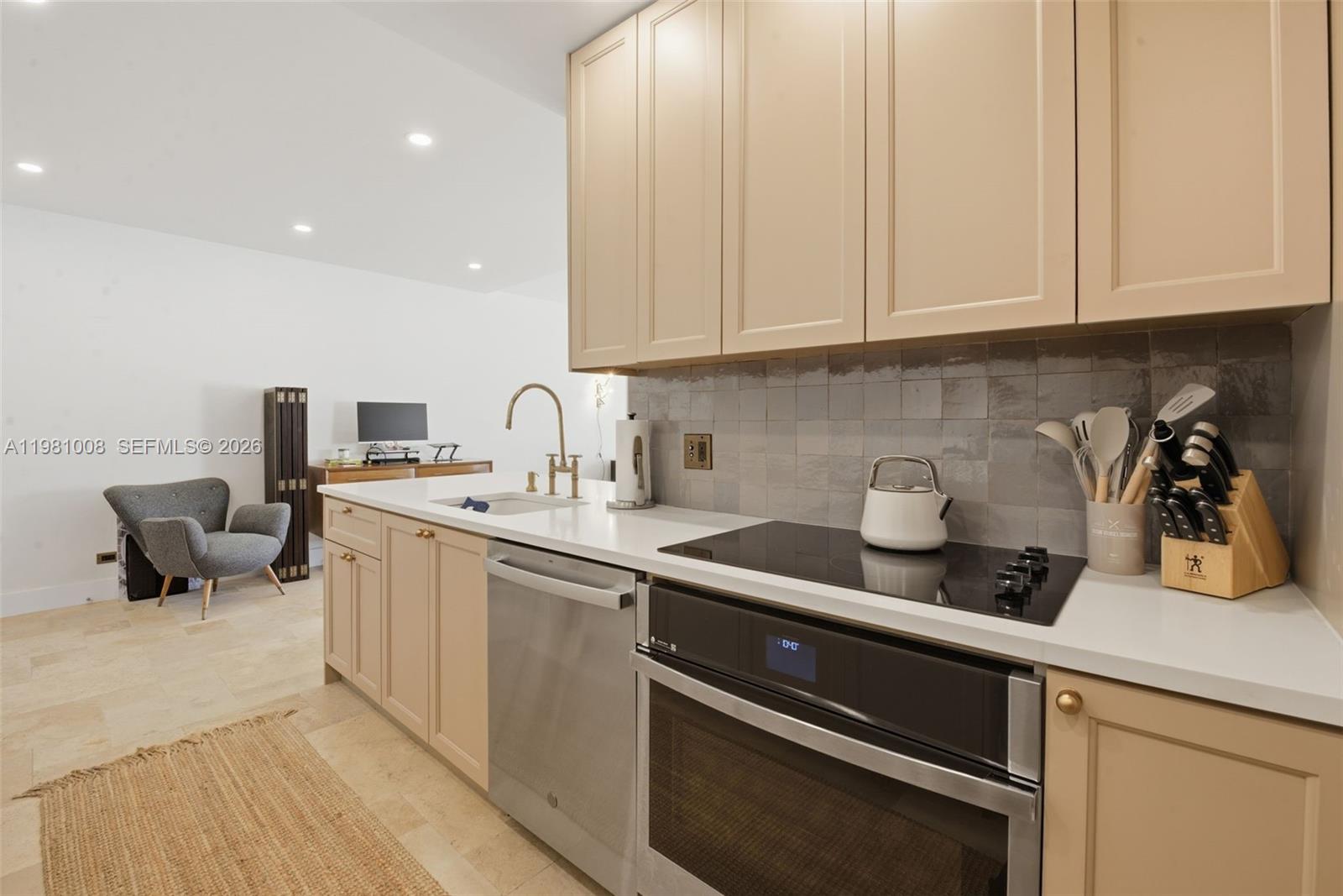 A kitchen features beige cabinets, stainless steel appliances, a white countertop, and a tiled backsplash — 3 Island Ave # 06K, Miami Beach FL 33139, MIAMI BEACH, FL