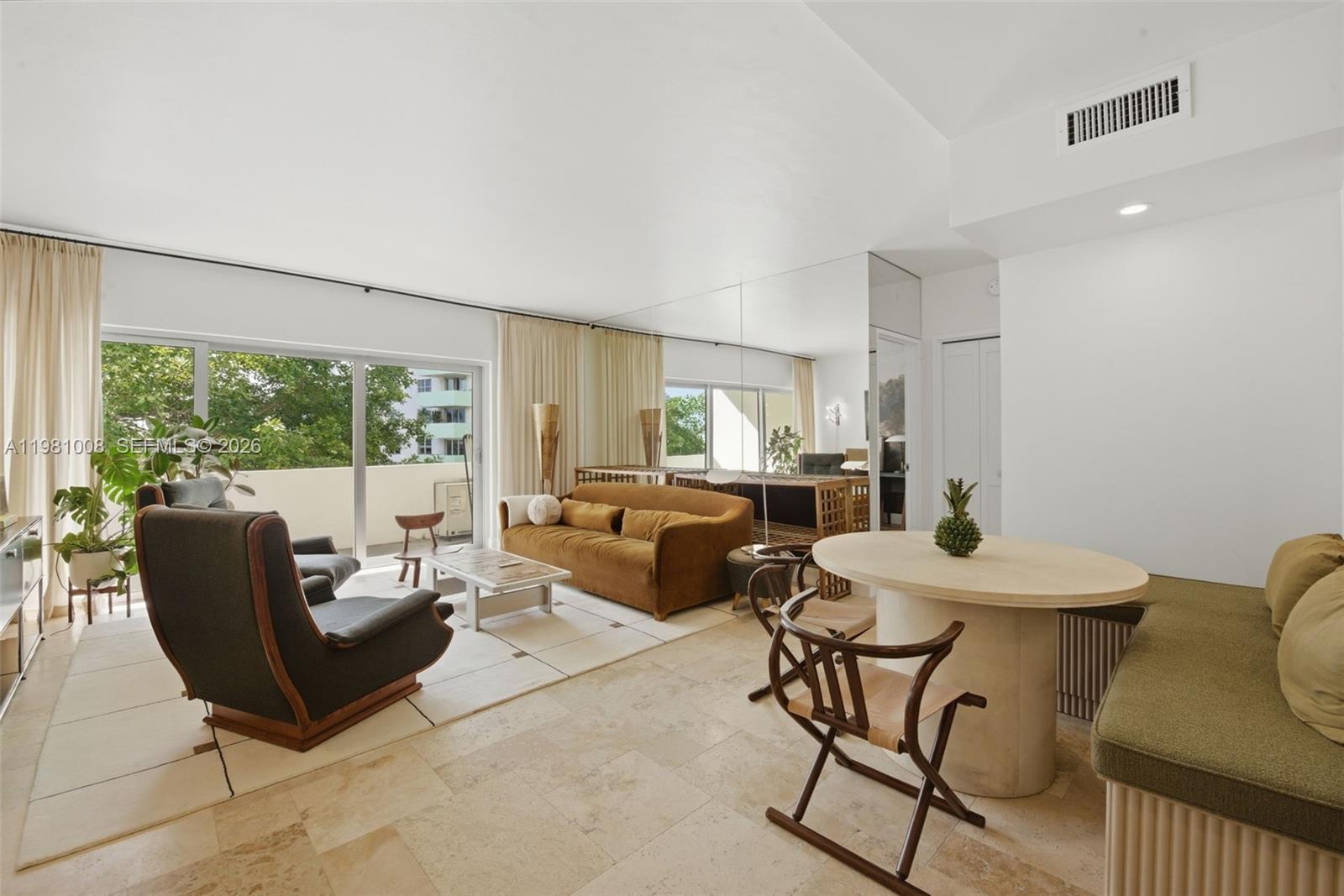 A living and dining area features travertine floors, a brown sofa, and a balcony view — 3 Island Ave # 06K, Miami Beach FL 33139, MIAMI BEACH, FL