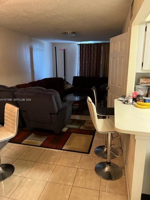 A living room with a dark sofa and recliner sits behind a kitchen breakfast bar — 2029 NW 46th Ave # E503, Lauderhill FL 33313, LAUDERHILL, FL