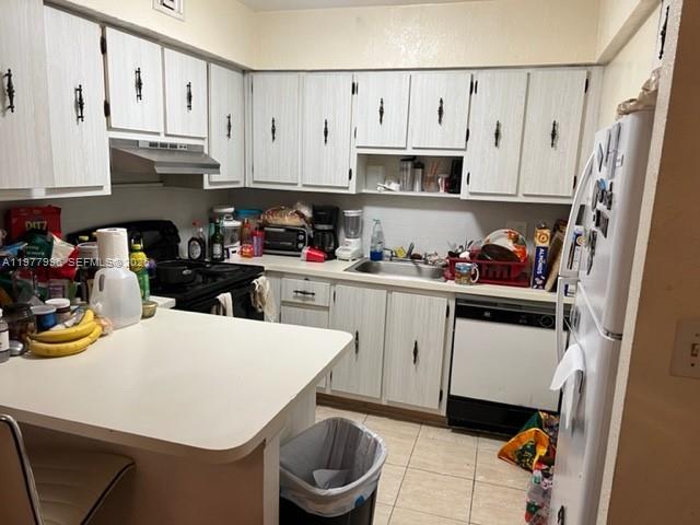 A kitchen features white cabinets, a peninsula counter, a dishwasher, and a refrigerator — 2029 NW 46th Ave # E503, Lauderhill FL 33313, LAUDERHILL, FL
