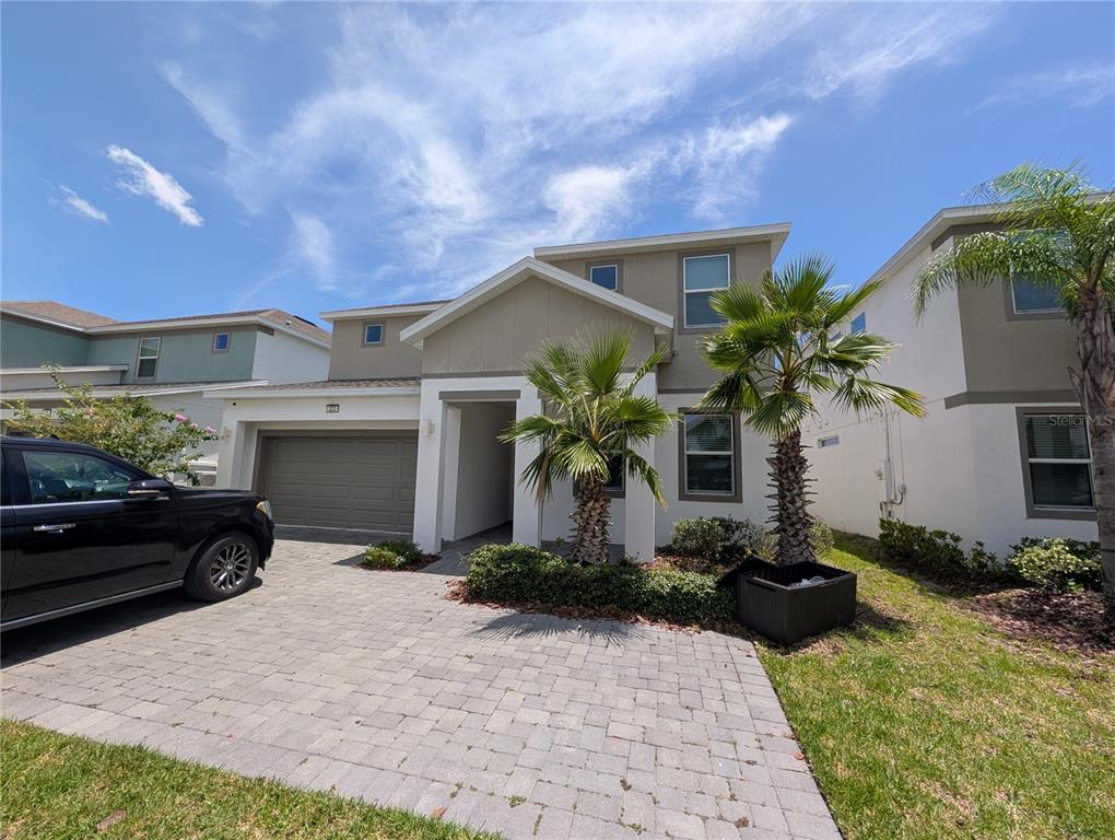 A two-story house with a paved driveway, a garage, and two palm trees in front — 222 MARCELLO BOULEVARD, KISSIMMEE, FL