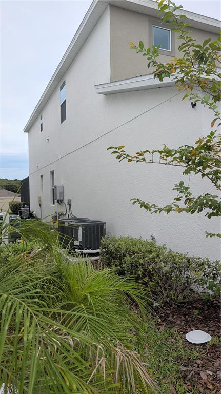 The side exterior of a two-story house features two air conditioning units and landscaping — 222 MARCELLO BOULEVARD, KISSIMMEE, FL