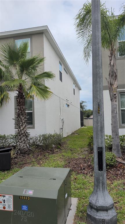 A side view of a two-story house with a palm tree and utility equipment nearby — 222 MARCELLO BOULEVARD, KISSIMMEE, FL