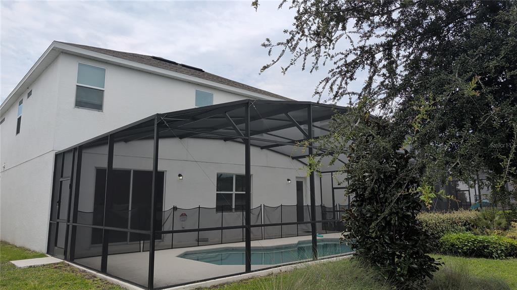 A two-story house features a screened-in pool enclosure and a small backyard — 222 MARCELLO BOULEVARD, KISSIMMEE, FL