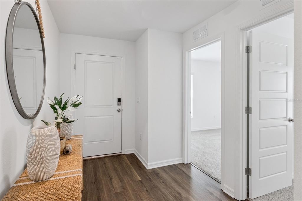 An entryway features a wood-look floor, a woven console table, a mirror, and two doorways — 761 GREENWAY BOULEVARD, LAKE WALES, FL