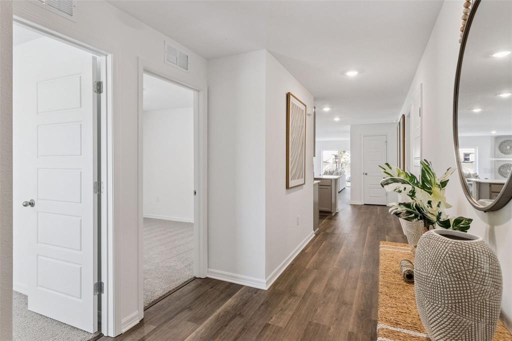 A hallway with wood-look flooring leads to an open living area and a carpeted bedroom — 761 GREENWAY BOULEVARD, LAKE WALES, FL