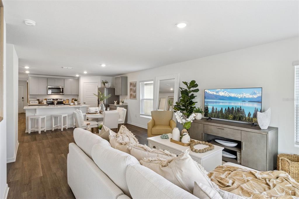A bright open-concept living room and kitchen with white cabinetry, wood flooring, and neutral furniture — 761 GREENWAY BOULEVARD, LAKE WALES, FL