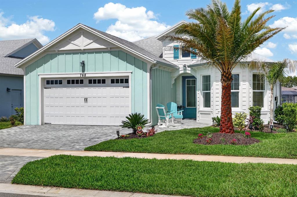 A light green house with a white garage, a palm tree, and two blue chairs — 768 MARGARITAVILLE AVENUE, DAYTONA BEACH, FL