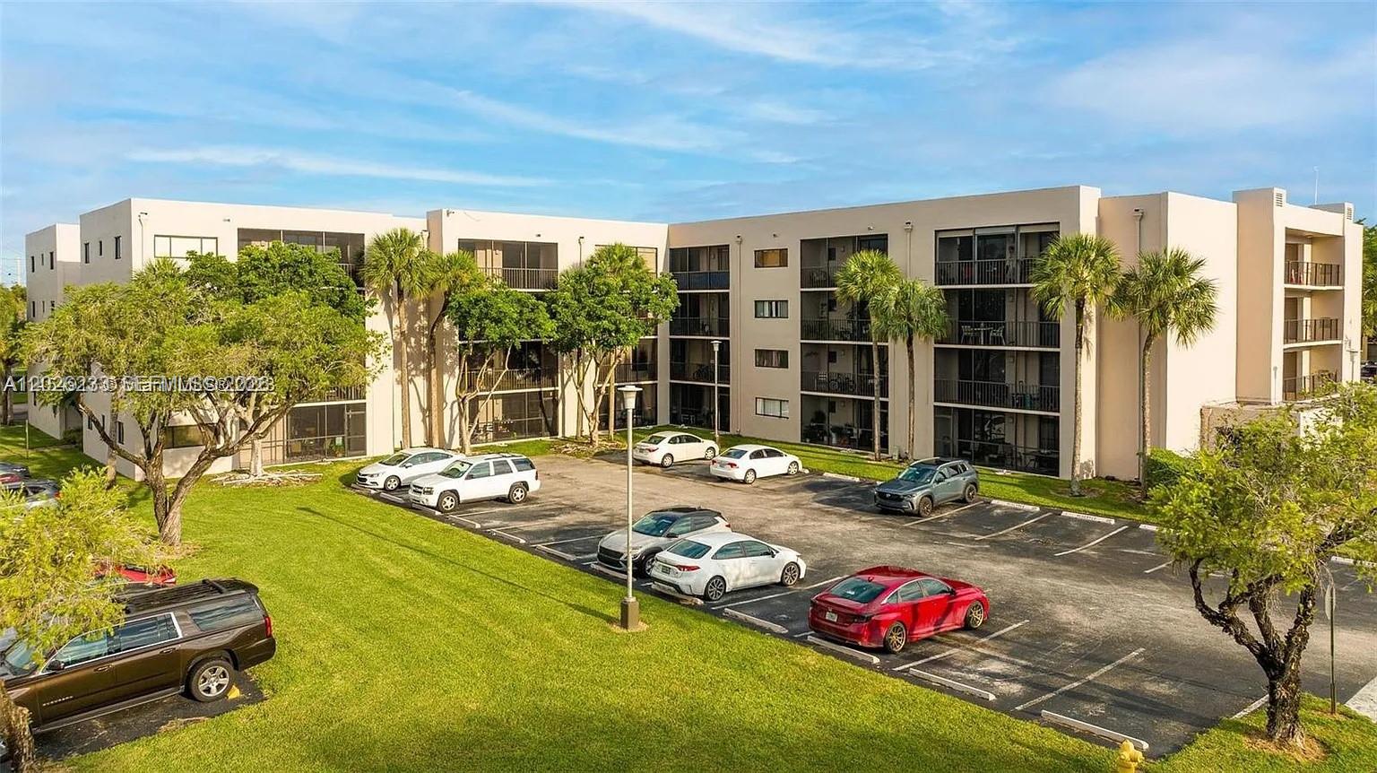 An exterior view of a multi-story apartment building with a parking lot in front — 8420 SW 133rd Ave Rd # 307, Miami FL 33183, MIAMI, FL