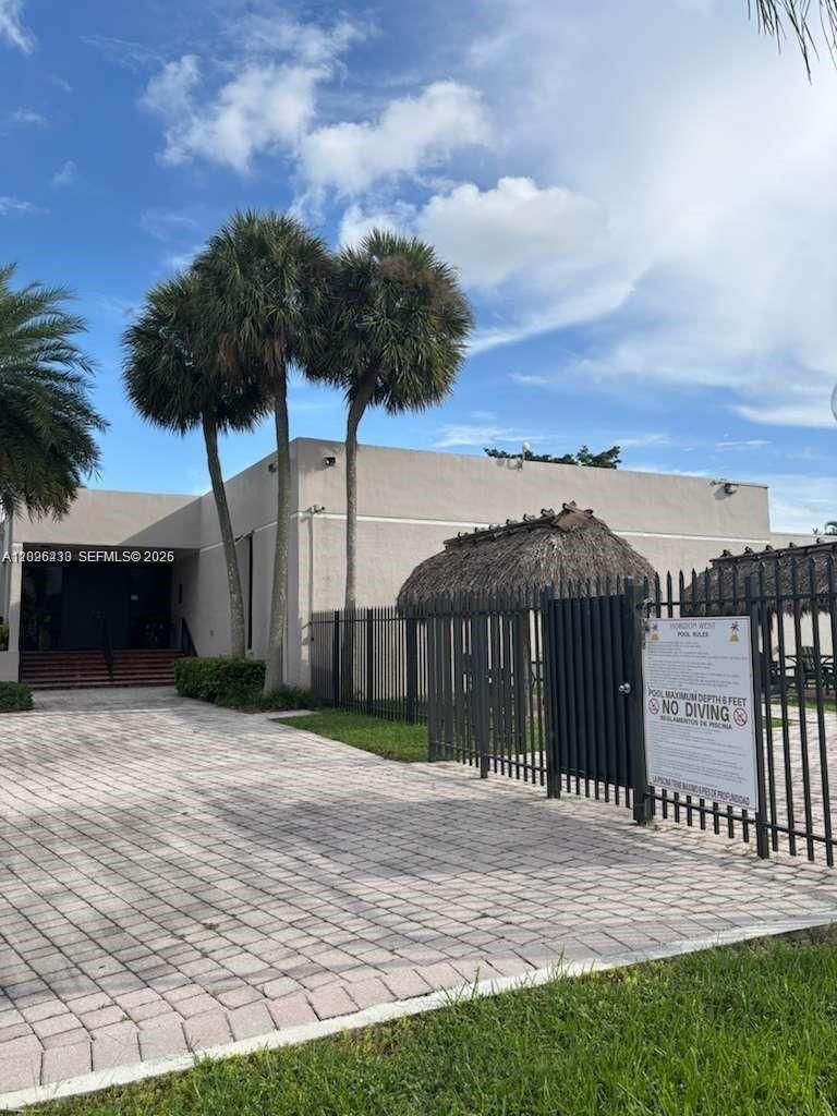 A paved driveway leads to a building entrance and a fenced pool area with tiki huts — 8420 SW 133rd Ave Rd # 307, Miami FL 33183, MIAMI, FL