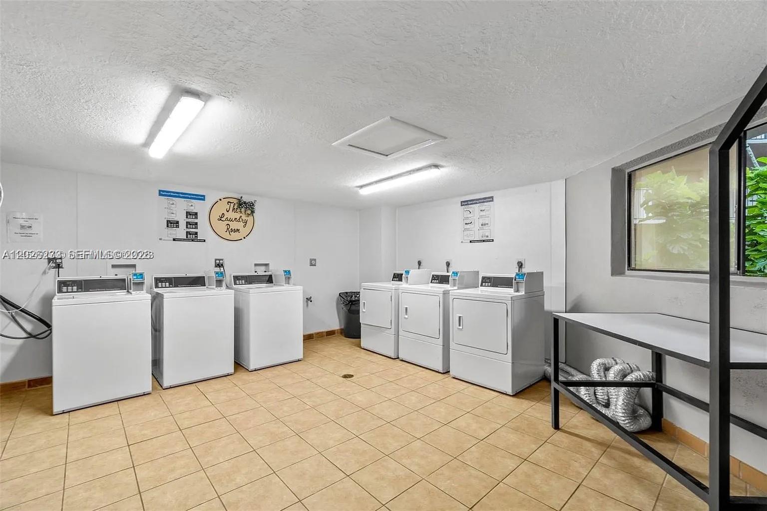 A laundry room features three white washing machines, three white dryers, and tile flooring — 8420 SW 133rd Ave Rd # 307, Miami FL 33183, MIAMI, FL