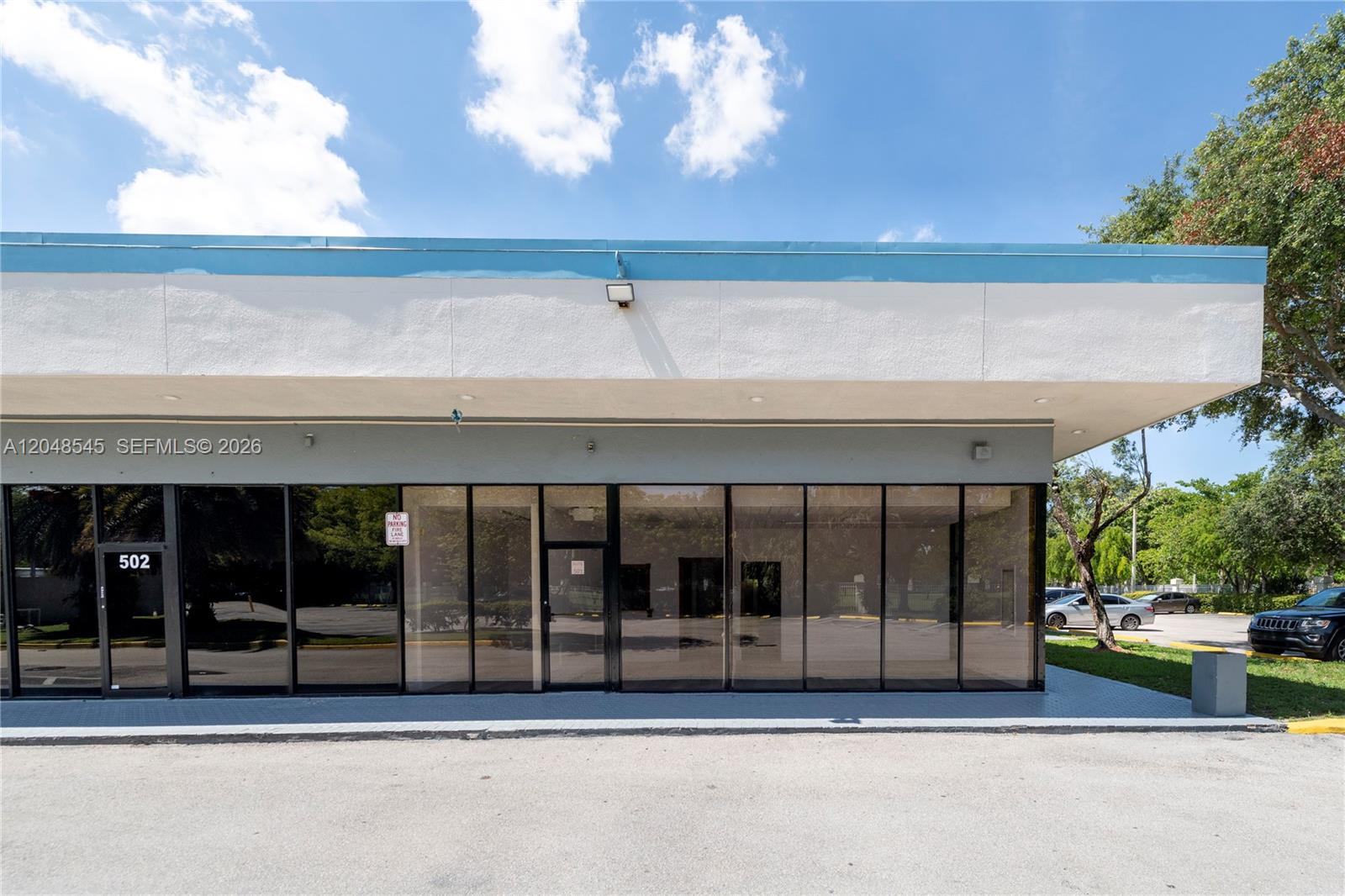 The exterior of a commercial building features a glass storefront with a blue roofline — 3801 N University Dr # 501, Sunrise FL 33351, SUNRISE, FL