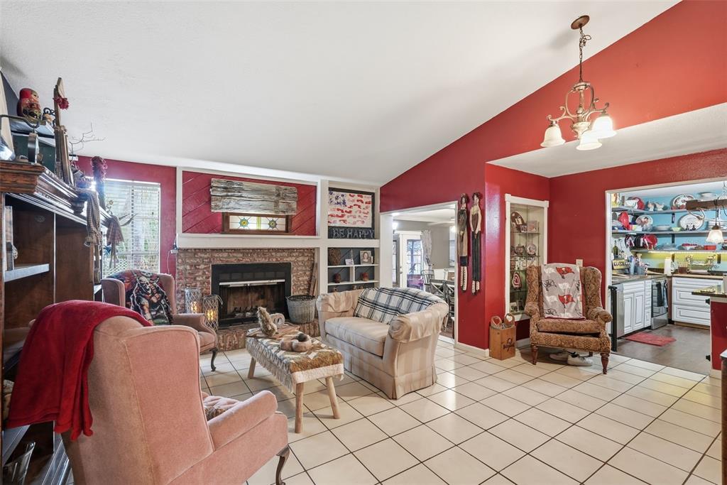 A living room with a brick fireplace, tiled floors, and red walls — 17603 CRANBROOK DRIVE, LUTZ, FL
