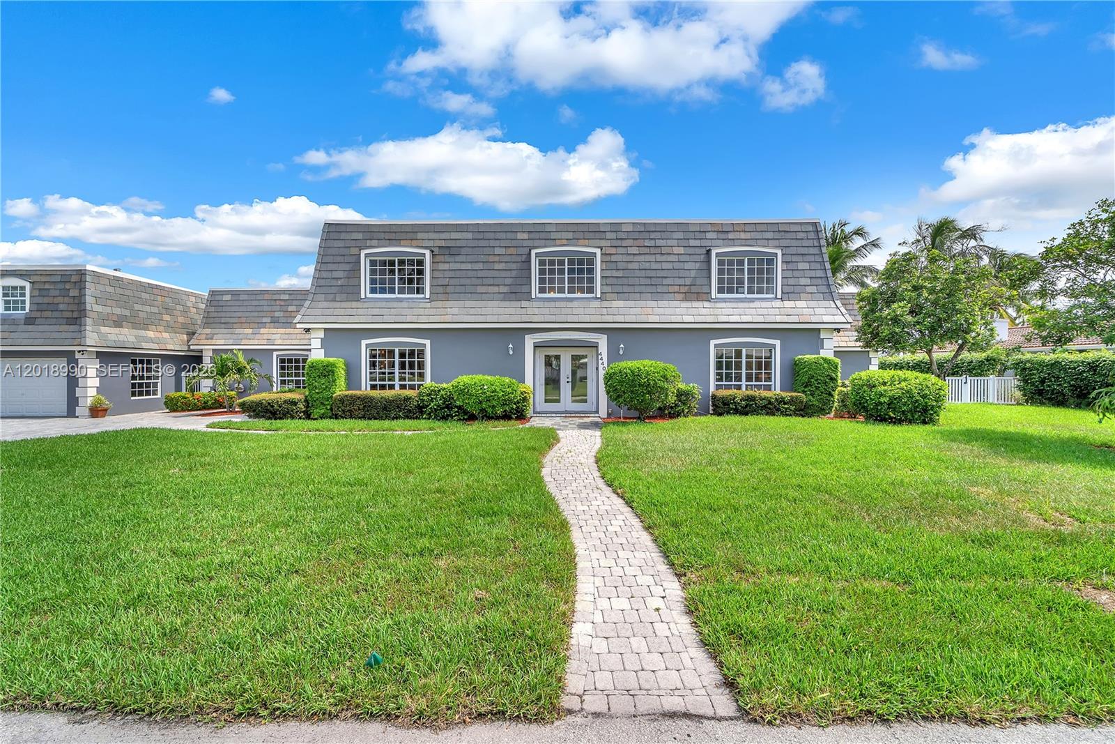 A two-story gray house with a mansard roof and a stone walkway in front — 4440 NE 23rd Ave, Lighthouse Point FL 33064, LIGHTHOUSE POINT, FL