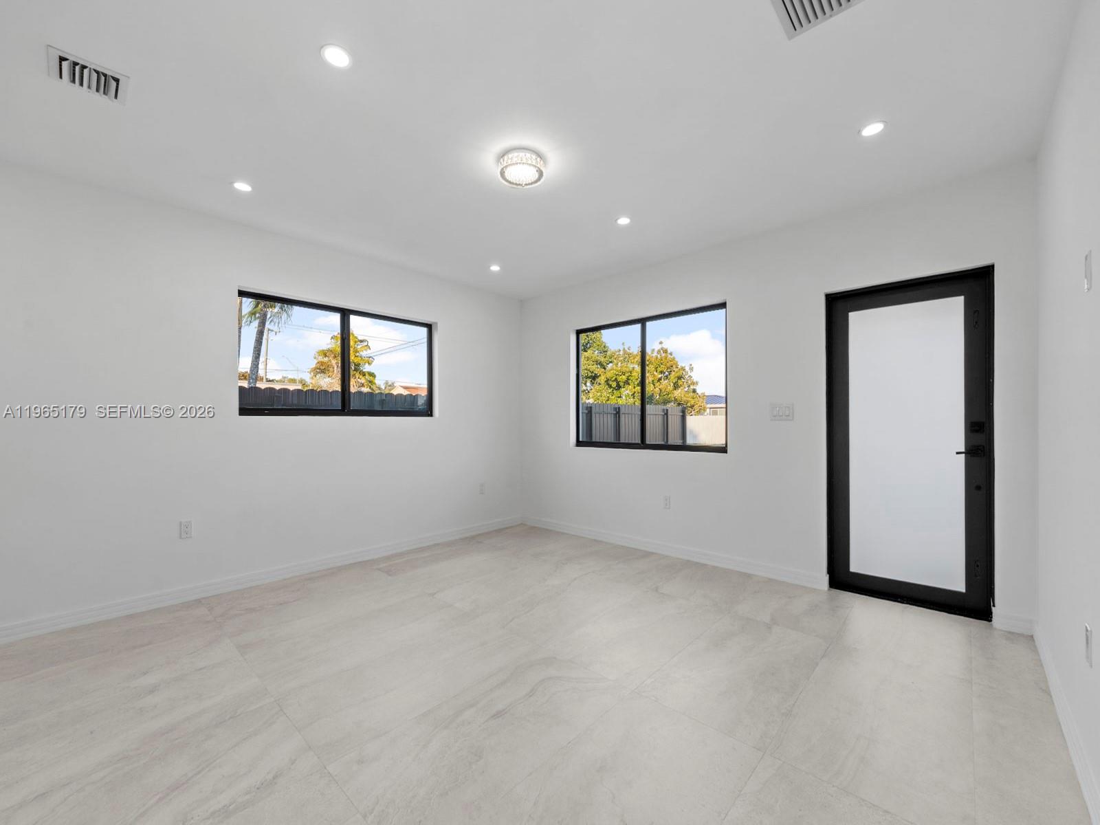 A bright, empty room features white walls, light tile flooring, recessed lighting, and black-framed windows — 3620 SW 92nd Ave, Miami FL 33165, MIAMI, FL